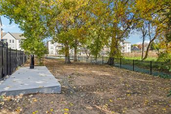 A park with trees and a concrete slab in front of a fence